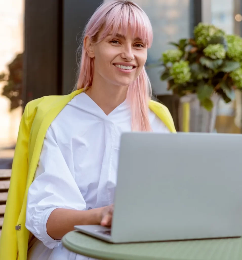 joyful young woman using laptop at outdoor cafe utc