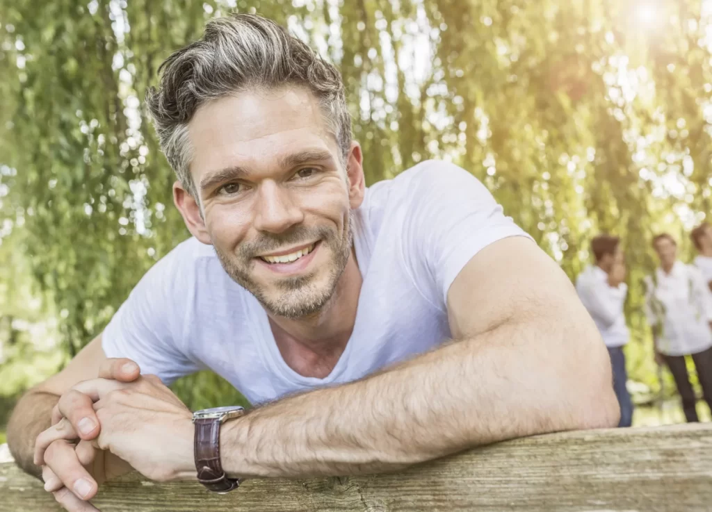 portrait of mid adult man leaning on fence in fore utc
