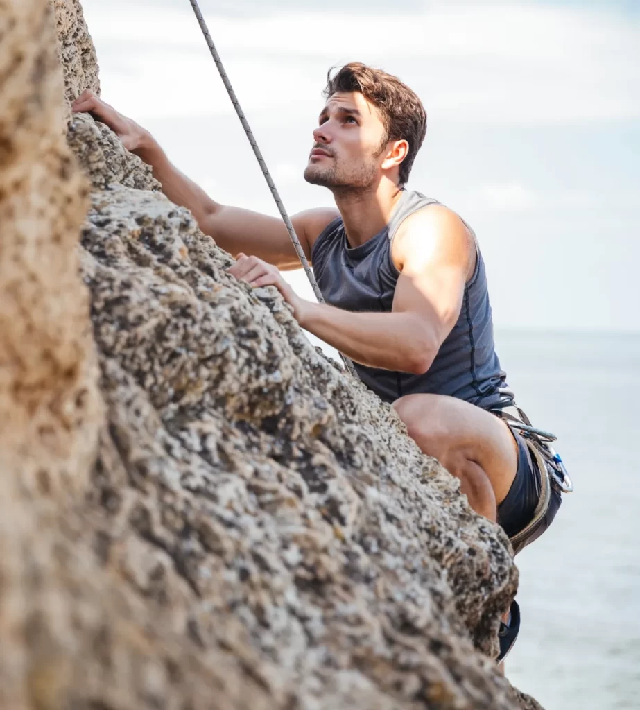 young man climbing natural rocky wall utc